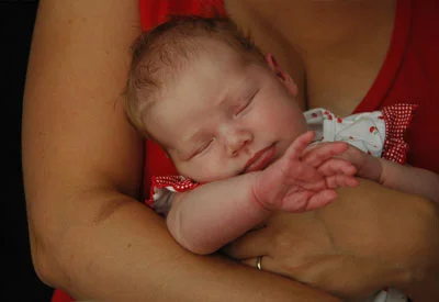 A sleeping newborn cradled in a parent's arms
